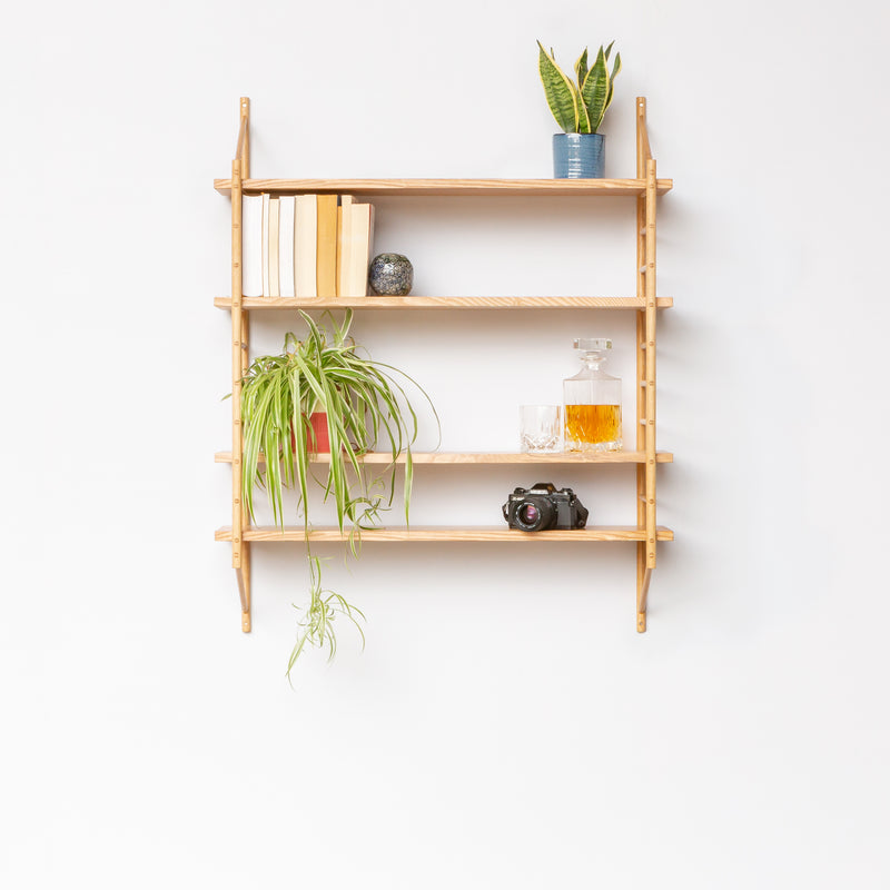 wall hung wooden ladder shelving with four shelves holding plants and books and camera