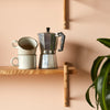 single wooden shelving with coffee mugs and mocha pot and plant